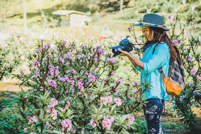 Side view of woman standing by flowering plants