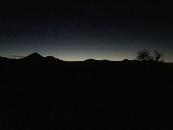 Silhouette landscape against clear sky at night