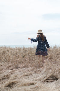 Rear view of woman with umbrella walking on beach