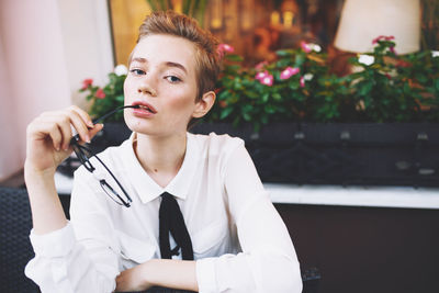 Portrait of young woman holding eyeglasses