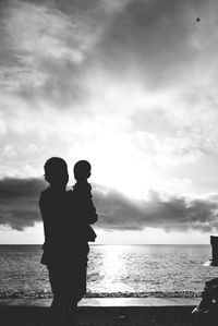 Rear view of couple standing at beach against sky