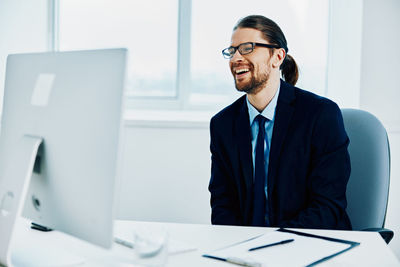 Smiling young man looking at computer screen in office