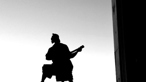 Low angle view of silhouette man standing against clear sky