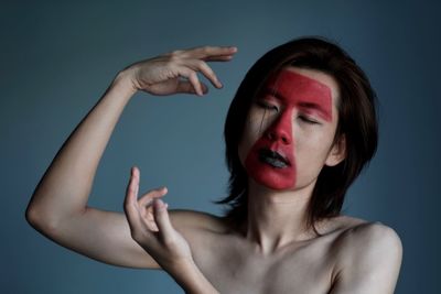 Close-up portrait of young woman against gray background