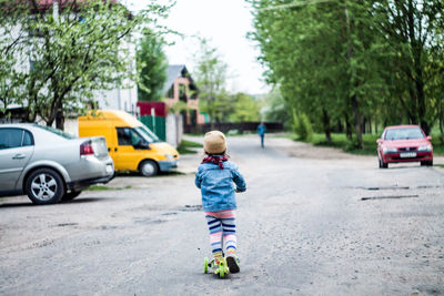 Rear view of boy with umbrella on street in city