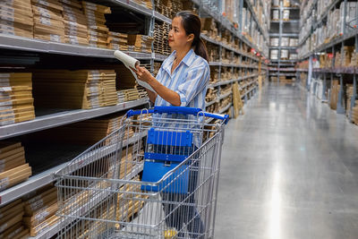 Woman writing while standing in warehouse