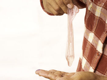 Close-up of hand holding umbrella over white background