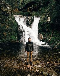 Man standing against waterfall in rainforest