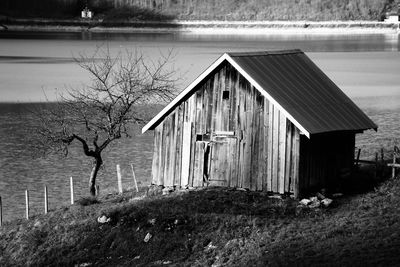 Wooden house by lake against trees in blackandwhite