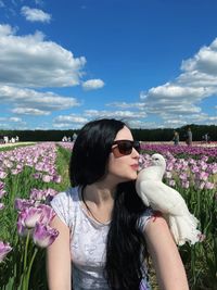 Portrait of young woman standing on field against sky