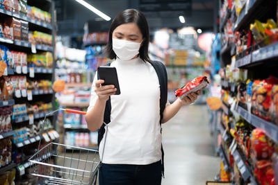 Full length of woman using smart phone at store