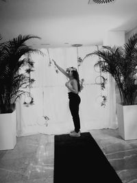 Full length of woman standing by palm tree