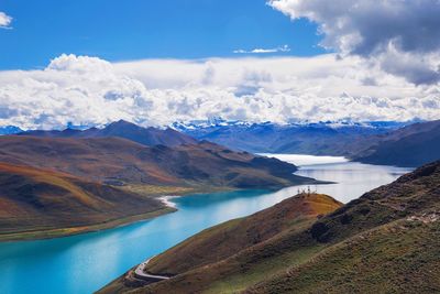 Scenic view of turquoise river amidst mountains against cloudy sky