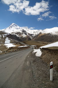 Road by snowcapped mountains against sky