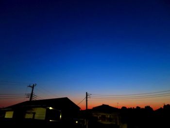 Silhouette houses against clear sky at sunset