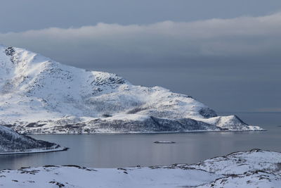 Scenic view of sea and snowcapped mountains against sky