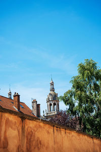 Low angle view of building and trees against blue sky