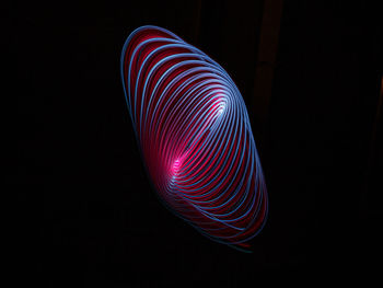 Low angle view of illuminated lighting equipment against black background