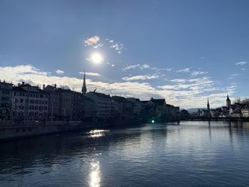 City at waterfront against cloudy sky