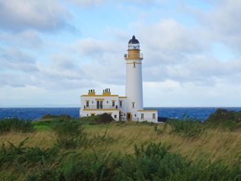 Lighthouse by sea against sky