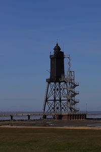 Lighthouse by sea against clear sky