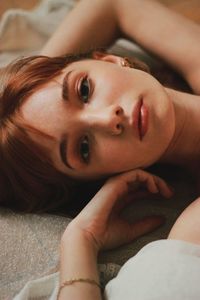 Portrait of young woman lying on bed at home