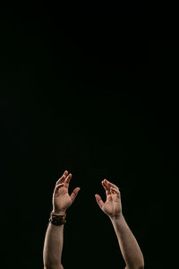 Low angle view of person hand against black background