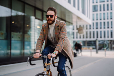 Full length of man riding bicycle on street