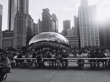 People at modern buildings in city against sky