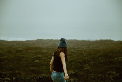 Rear view of woman standing on land against sky