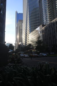 Cars on road by buildings in city against sky