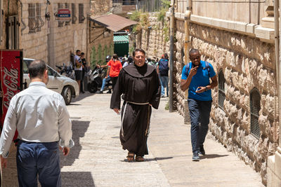 Rear view of people walking on street in city