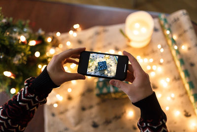 Man taking pictures on smartphone carefully wrapped christmas present