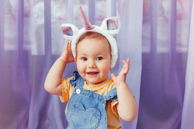 Portrait of cute baby girl wearing unicorn hat at home