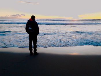 Silhouette of people standing on beach at sunset