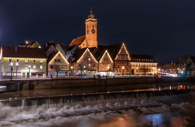 Illuminated building by river against sky at night in nürtingen