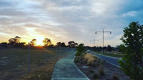 Country road against cloudy sky at sunset