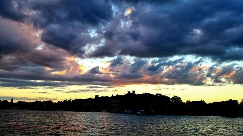 Scenic view of river against cloudy sky at sunset