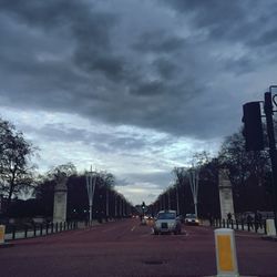Cars on road against cloudy sky
