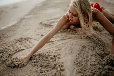 Full length of woman sitting on sand at sandy beach
