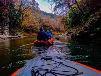 Rear view of men sitting on boat in river