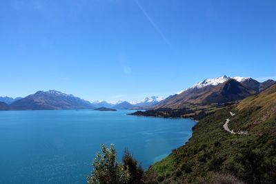 Scenic view of lake and mountains against clear blue sky