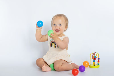 Portrait of cute girl playing with toy against white background