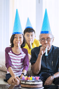 Grandparents and grandchildren sitting with birthday cake at home