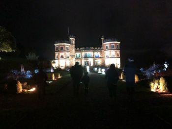 People on illuminated building at night