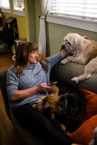 Mid 40's woman sitting on chair with her two large dogs