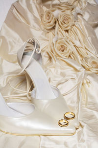 Close-up of wedding rings on high heels and dress
