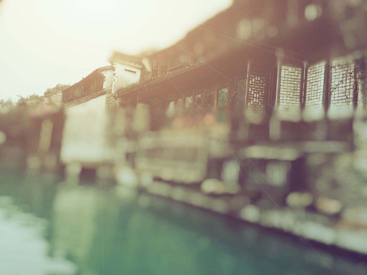 architecture, built structure, building exterior, water, bridge - man made structure, city, river, reflection, connection, selective focus, focus on foreground, waterfront, outdoors, sky, railing, building, day, no people, focus on background, clear sky