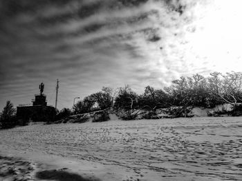 Trees on snow covered field against sky