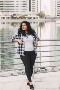 Portrait of young woman standing against building
